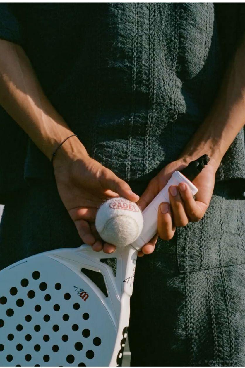 Joueur tenant une balle et une raquette de padel