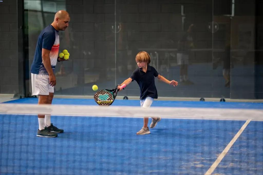 Coach de padel et jeune joueur pendant un cours