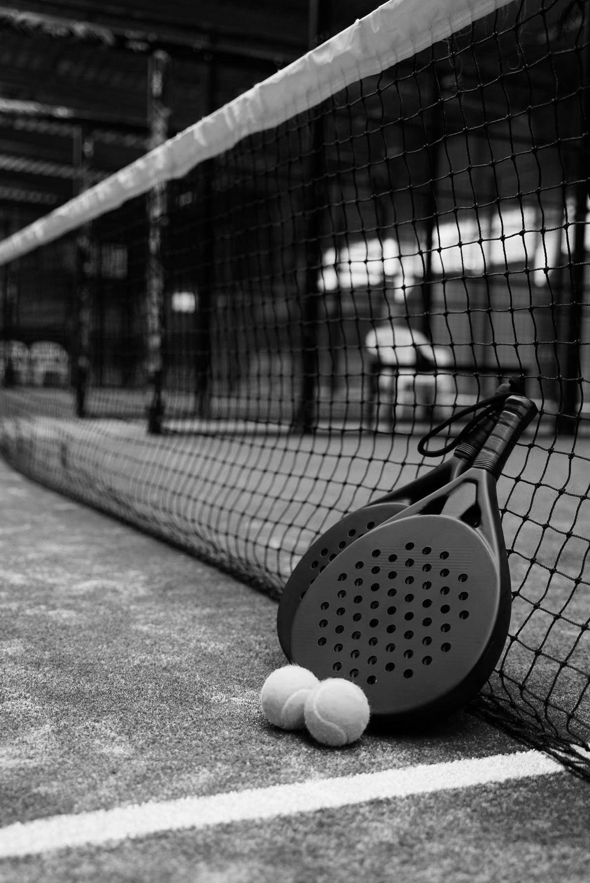 Raquette de padel et balles posées au pied du filet