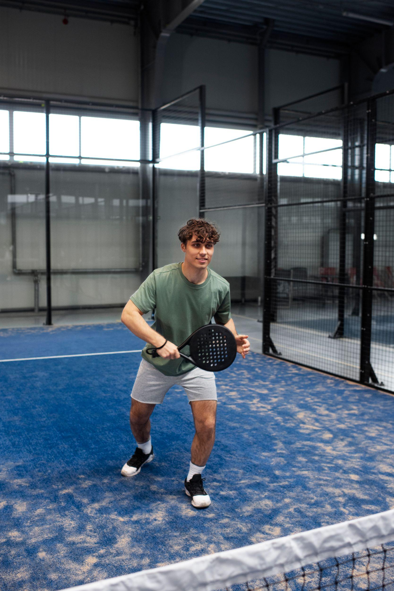 Joueur de padel en position d’attente sur une piste couverte
